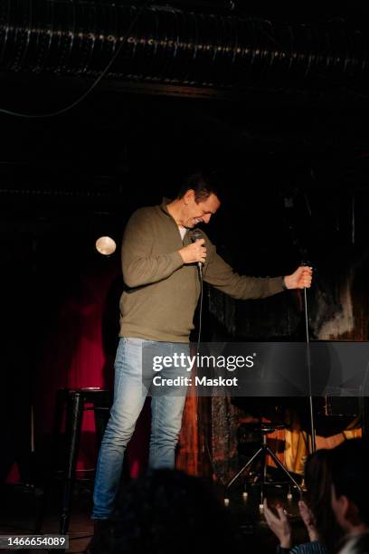 happy senior male comedian performing on stage in theater - stand up comedy stockfoto's en -beelden