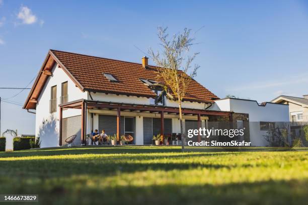 large house with terrace,two boys sitting on chairs on the terrace and surfing the net on their phone,large backyard,low angle view,focus on background - facade blinds stock pictures, royalty-free photos & images