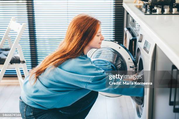 young woman doing laundry at home. - lavadora fotografías e imágenes de stock