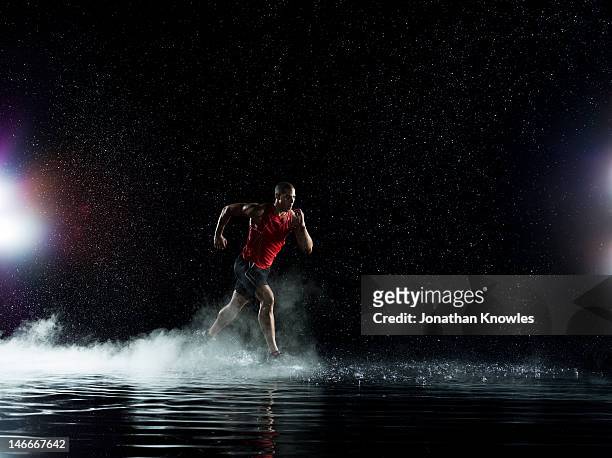 athlete running in water in rain at night - forward athlete stock pictures, royalty-free photos & images