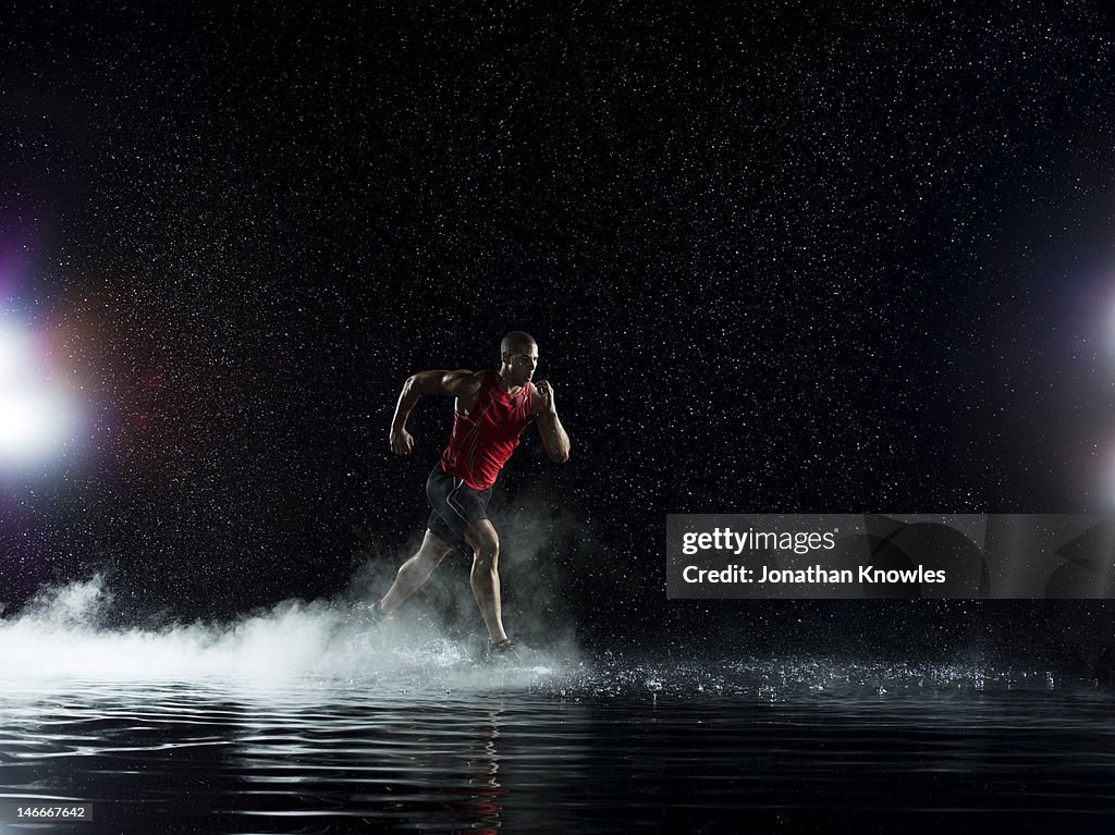 Athlete running in water in rain at night