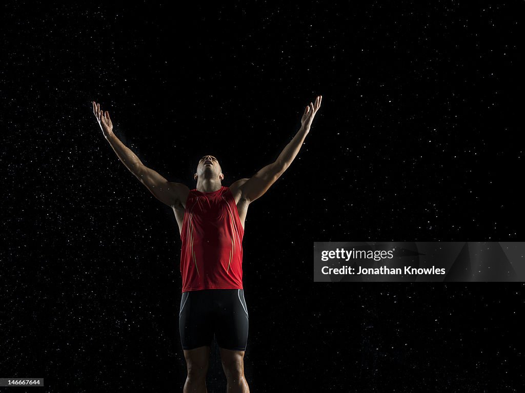 Athlete holding arms in the air in rain