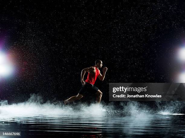 athlete running through water, in rain at night - dry ice black background stock pictures, royalty-free photos & images