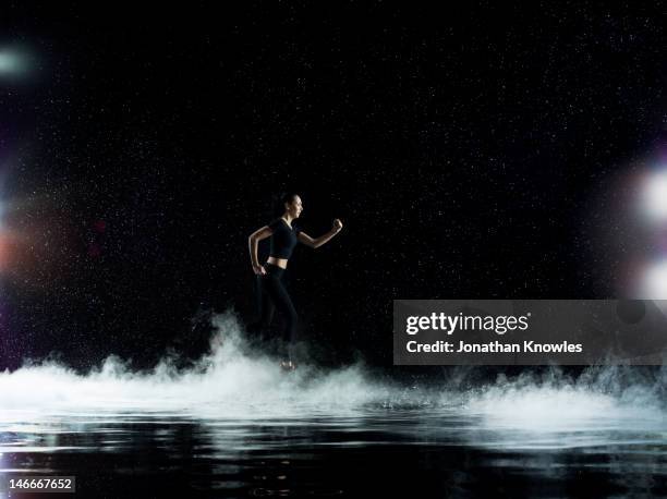 female athlete running through rain, misty night - person spot light photos et images de collection