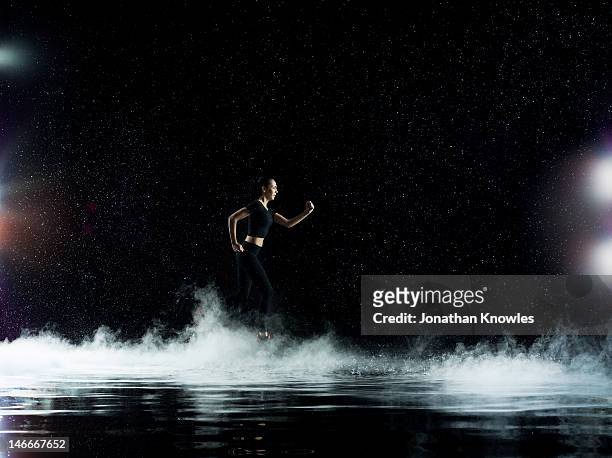 female athlete running through rain, misty night - forward athlete stockfoto's en -beelden