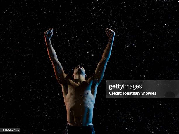 male athlete raising arms in victory in rain - attitude stock pictures, royalty-free photos & images