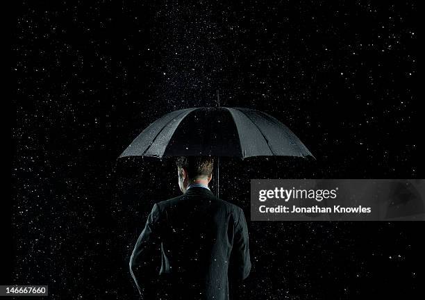 back of a businessman under umbrella - risk economy stock pictures, royalty-free photos & images