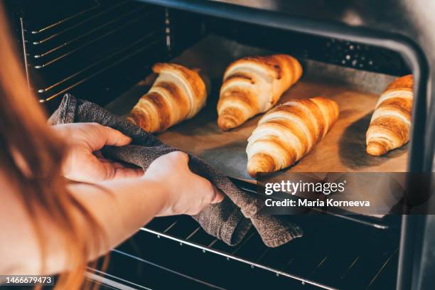 woman removing baked croissants tray from an oven. - thick white women fotografías e imágenes de stock