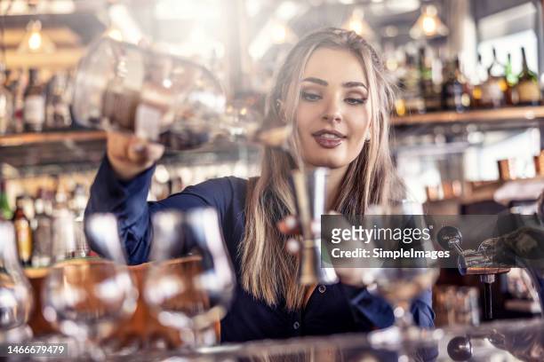 an experienced young bartender pours an alcoholic drink into a measuring cup and then into a glass at the bar. - barman tequila stockfoto's en -beelden