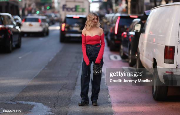 Xenia Adonts seen wearing a shoulder free red longsleeve shirt, a dark blue Otto Linger oversized jeans, black boots and a black Louis Vuitton bag...