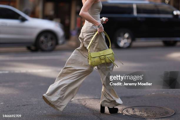Mary Leest seen wearing a matching shoulder free beige shirt and oversized beige pants, dark shades and a green bag before the Brandon Maxwell show...