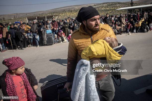 Syrian man carries his baby to the border gate as Syrians effected by the earthquake wait to cross from Turkey's Cilvegozu border crossing to the Bab...