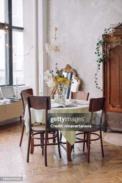 vase of rustic flowers on a dining table in a dining room - kronleuchter stock-fotos und bilder