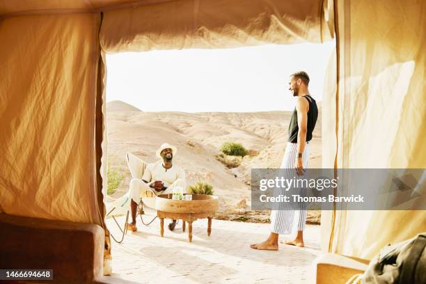 wide shot smiling couple relaxing outside of tent while at desert camp - eco tourism stock pictures, royalty-free photos & images
