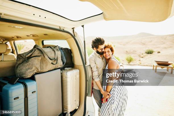 medium wide shot portrait couple standing next to van loaded with luggage - wide load stock pictures, royalty-free photos & images