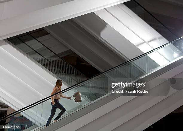 a young girl with a handbag runs up the escalator - escalator photos et images de collection