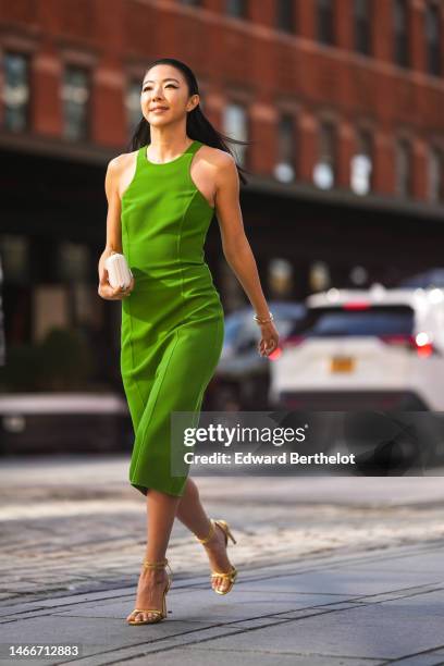 Yuwei Zhangzou wears a green halter-neck / midi tube dress, a gold Juste Un Clou bracelet from Cartier, a gold and diamonds Love bracelet from...