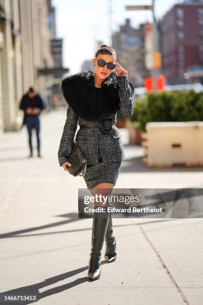 Michelle Salas wears black sunglasses, a black t-shirt, a gray and black checkered print pattern wool with a black large fur collar jacket, a...