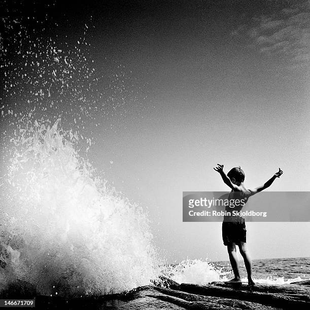 boy in front of wave. - courage photos et images de collection