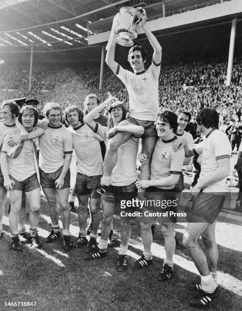 Arsenal Football Club team captain Frank McLintock holds aloft the Football Association trophy while being carried on the shoulders of team-mates...