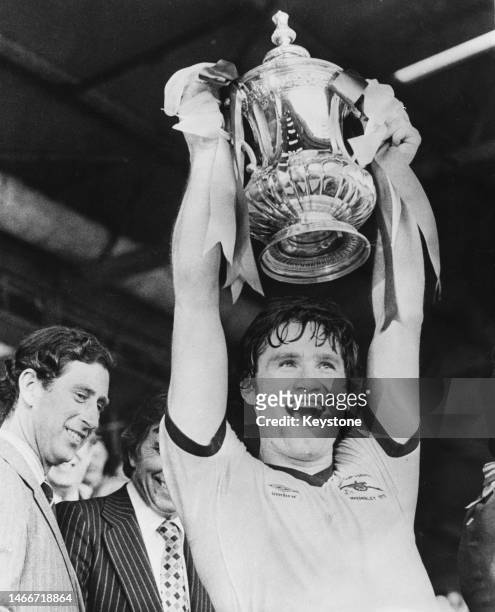 Prince Charles, Prince of Wales looks on as Arsenal Football Club team captain Pat Rice lifts the Football Association trophy after winning the FA...
