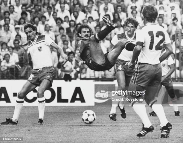 England footballers Phil Thompson, #4 Terry Butcher and Mick Mills surround the mid air Spanish striker Jesús María Satrústegui during their Group B...