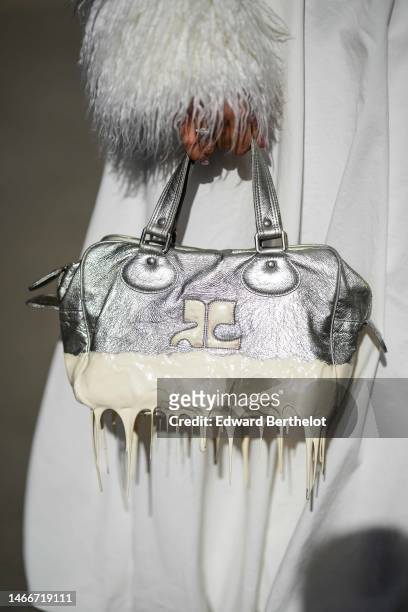 Guest wears a beige suede with embroidered white feathers collar and wrists zipper jacket, a white long V-neck / midi dress, a silver shiny leather...