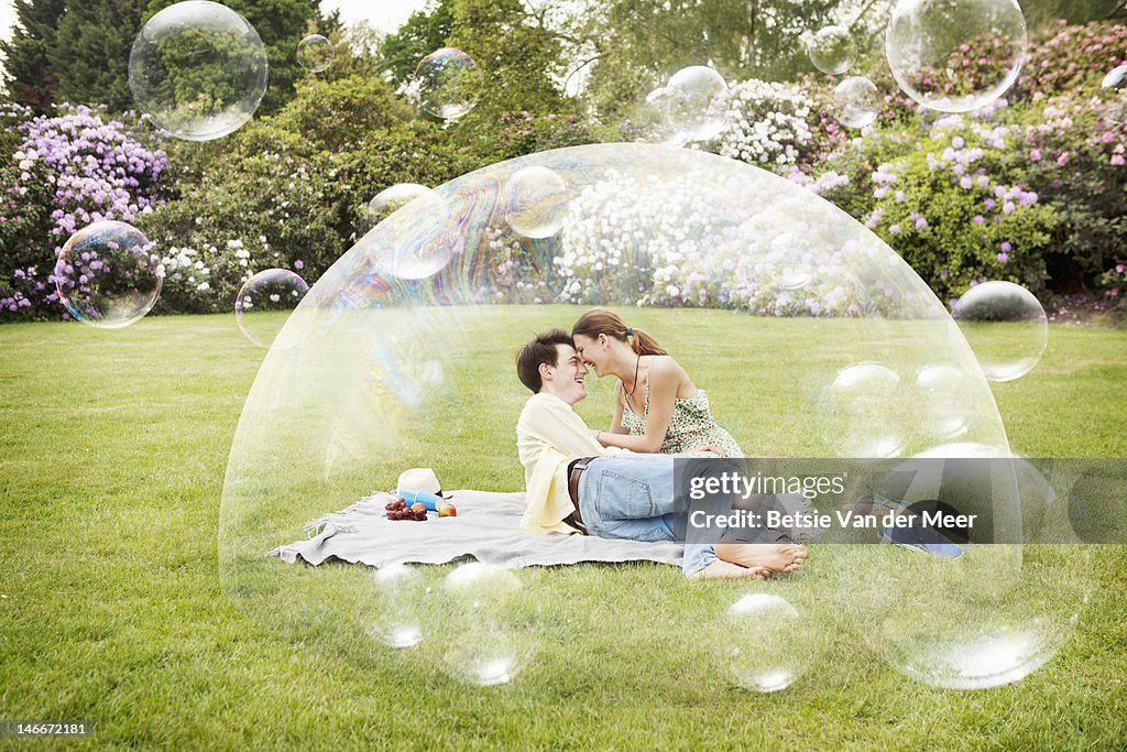 Couple having picnic surrounded by bubbles.