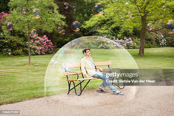 man listening to music sitting in bubble. - surreal stock-fotos und bilder