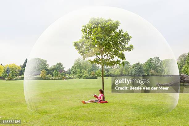 woman reading book in park in large bubble - protection imagens e fotografias de stock