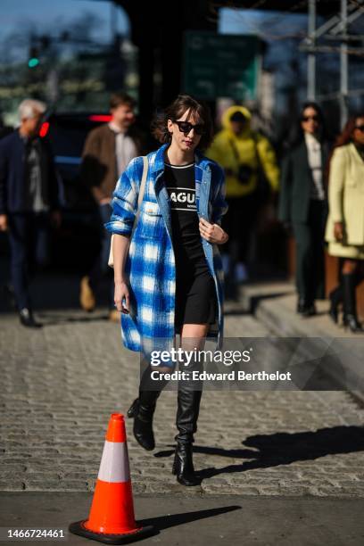 Guest wears black sunglasses, a black with white and red inscriptions print pattern t-shirt, a blue and white checkered print pattern wool long shirt...