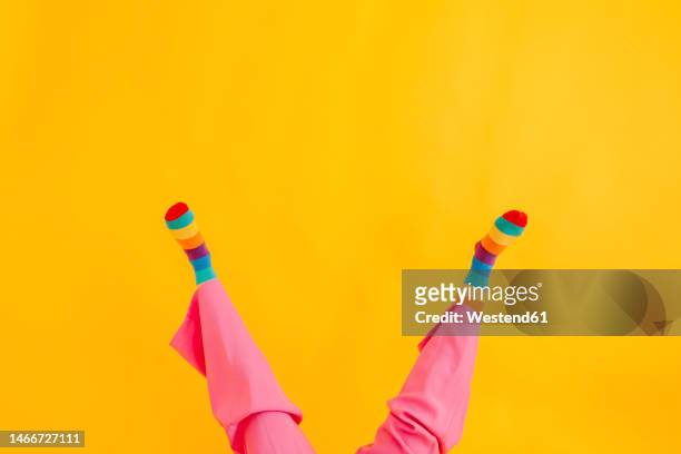 feet of woman wearing multi colored socks against yellow background - legs in stockings stock pictures, royalty-free photos & images