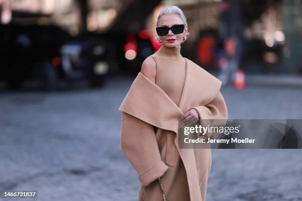 Ashley Graham seen wearing an oversized beige coat, a beige dress, a beige bag and beige boots with black shades before the Michael Kors show on...