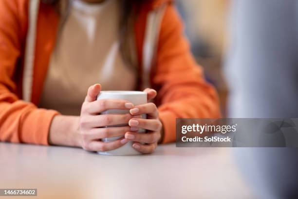 ängstlich eine tasse tee in der hand halten - hot beverage stock-fotos und bilder