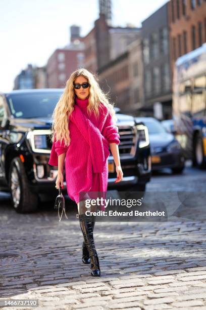 Emili Sindlev wears black sunglasses, black earrings, a neon pink ribbed wool turtleneck short pullover dress, a matching neon pink ribbed wool large...