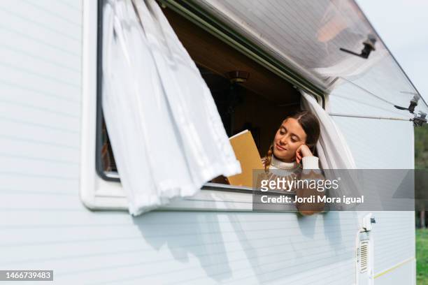 beautiful woman living an alternative lifestyle, enjoying a good book in a camper. - love books stock-fotos und bilder