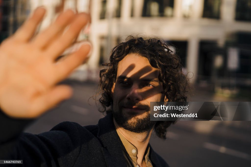 Businessman shielding eyes on street at sunset