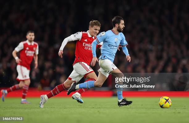 Of Manchester City runs with the ball whilst under pressure from Martin Odegaard of Arsenal during the Premier League match between Arsenal FC and...