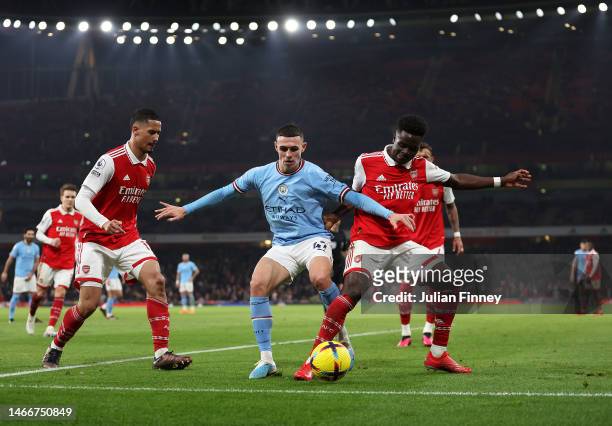 Phil Foden of Manchester City is challenged by Bukayo Saka of Arsenal during the Premier League match between Arsenal FC and Manchester City at...