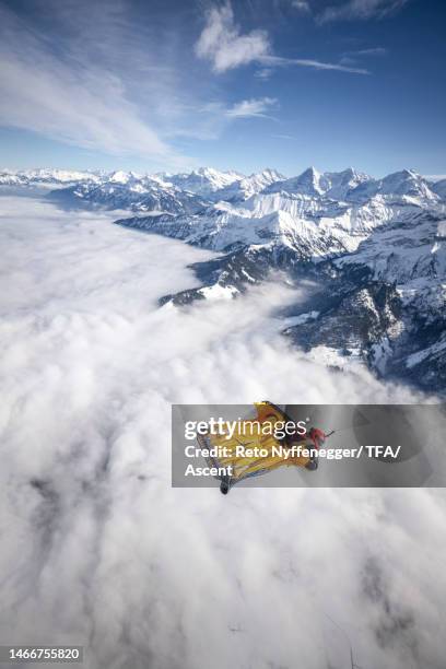 wingsuit flier sails high above the mountains in winter - mountain peak above clouds stock pictures, royalty-free photos & images