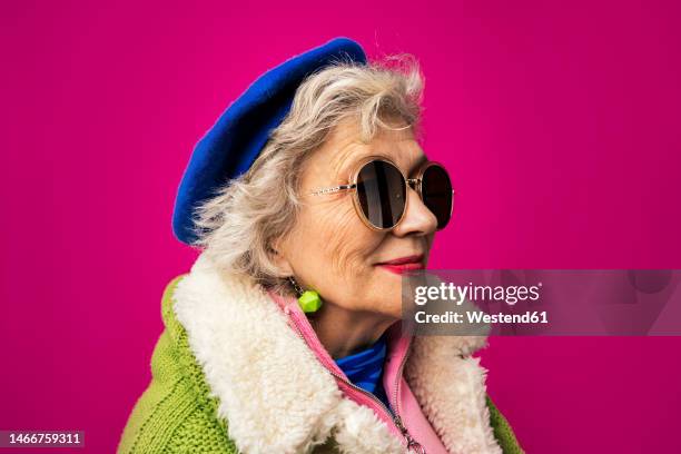 fashionable woman wearing sunglasses against pink background - coole oma stock-fotos und bilder