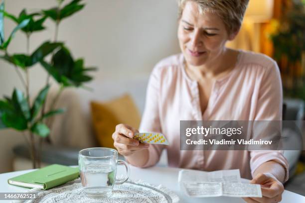 a smiling woman looking at her hormone pills - hrt pill stockfoto's en -beelden