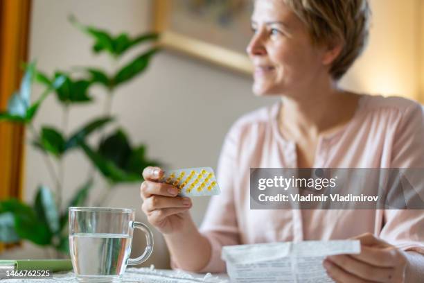 a smiling woman is relieved to get her hrt pills - hrt pill stockfoto's en -beelden