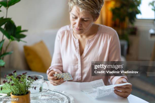 blisterpackung mit pillen in der hand halten und medizinische anweisungen lesen - nebenwirkungen von medikamenten stock-fotos und bilder