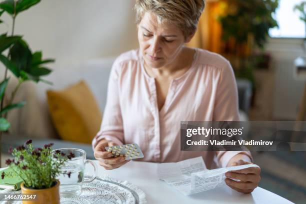 holding blister pack with pills in hand and reading medical instructions - hot flash stock pictures, royalty-free photos & images