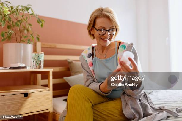 smiling woman reading instructions on estrogen gel - terapia hormonal imagens e fotografias de stock