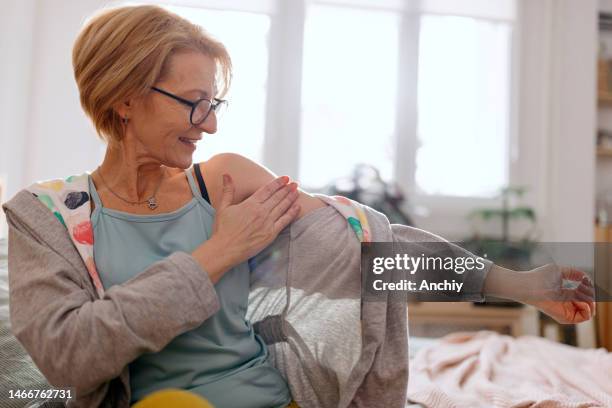 woman rubbing gel into the outside of the upper arm - hormone therapy stock pictures, royalty-free photos & images