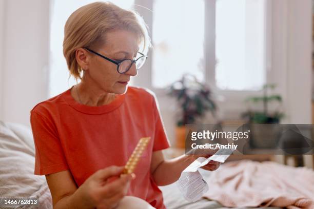 woman reading a prescription that came with medicine pills for hormone replacement therapy - hrt pill stockfoto's en -beelden