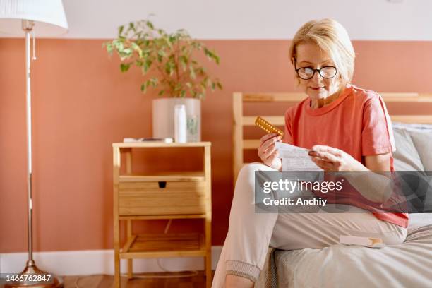 woman reading a prescription that came with medicine pills for hormone replacement therapy - hormona imagens e fotografias de stock