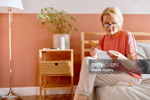 woman reading a prescription that came with medicine pills for hormone replacement therapy - hrt pill 個照片及圖片檔